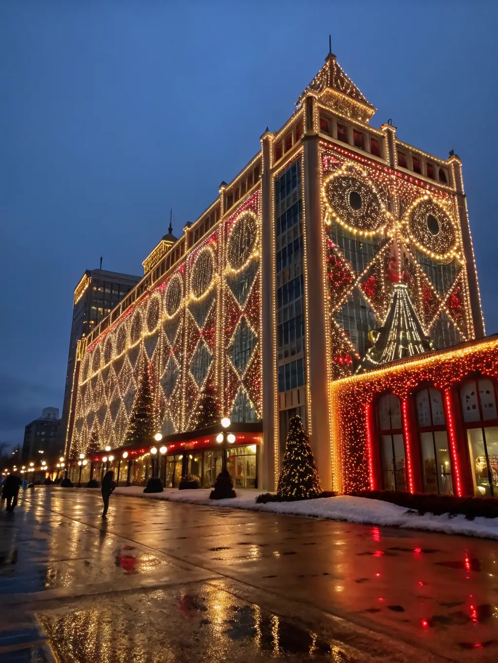 A commercial building facade illuminated with permanent holiday lighting, enhancing its nighttime appearance and attracting visitors, showcasing the versatility of the lighting systems.